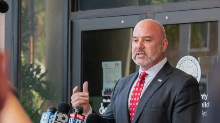 Florida CFO Slams City of Miami Over Explosive Spending: ‘If This Were a Business, It’d Be Bankrupt’ A man in a suit and red tie speaks passionately at a microphone array outside a building, conveying seriousness.