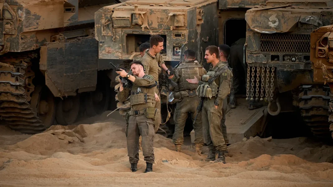US Deploys CENTCOM Troops to Israel to Monitor Trump-Brokered Gaza Ceasefire A group of soldiers in military gear stands in a sandy environment near armored vehicles