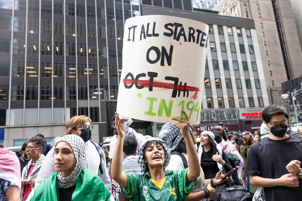 People gathered in the street, displaying various signs, actively participating in a demonstration or rally.