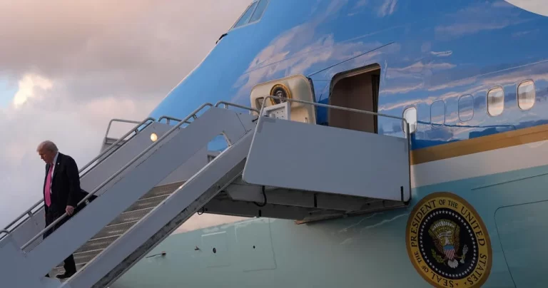 A person in a suit walks down the steps from Air Force One, with the airplane's blue exterior and presidential seal visible.
