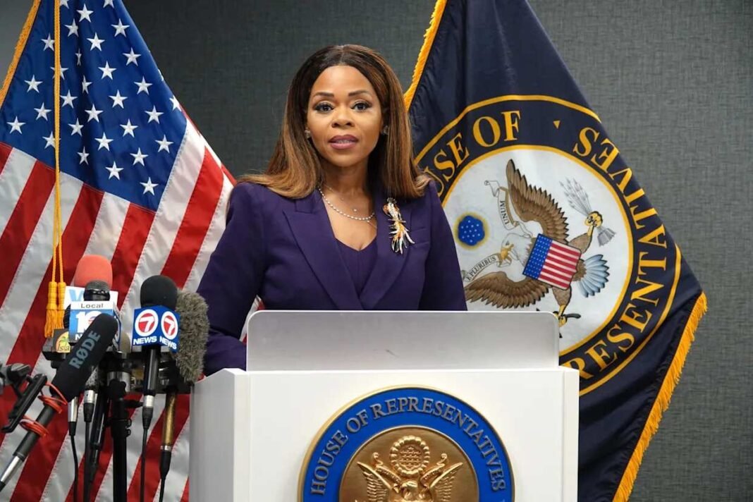 florida-congresswoman-indictment-doj-fbi A woman in a purple suit stands behind a podium marked