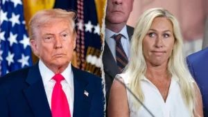 Two individuals stand side by side, dressed in formal attire, with the American flag and a presidential seal in the background.