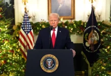 Trump Slams Washington Failure as Democrats Melt Down Over White House Address A person stands behind a podium with the presidential seal, surrounded by festive decorations and American flags.