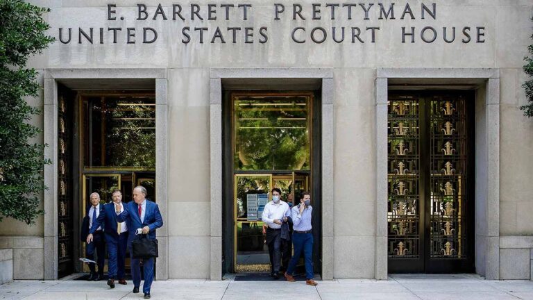 E. Barrett Prettyman U.S. Courthouse entrance with five people exiting, three in suits, two in casual wear.