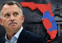 David Jolly Faces Criticism Over Political Switch in Florida Governor Race Man in suit stands before dark background with Florida map showing red and blue voting districts and a government building in grayscale.