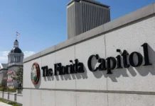 Florida Lawmakers Reach Final Budget Deal After Extended Negotiations The Florida Capitol building with its iconic dome and tower viewed from the side, featuring a sign reading 'The Florida Capitol' under a clear blue sky