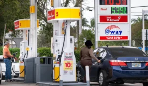 People refuel cars at a Shell gas station with prices showing $4.09 for regular and $5.39 for diesel fuel.