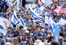 NYC Mayor Zohran Mamdani Skips Israel Day Parade, Breaking Longstanding Political Tradition Crowd of people wearing blue and white, waving Israeli and American flags, participating in a public event
