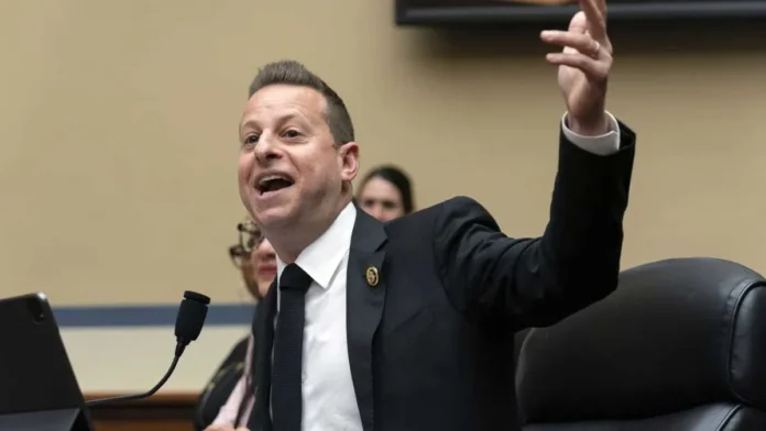 jared-moskowitz-google-news-1200x675 Person in a suit speaking and gesturing with one hand raised, seated at a desk with a microphone and a tablet.