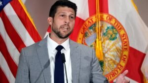 Florida Attorney General James Uthmeier speaks at a podium with American and Florida flags behind him.