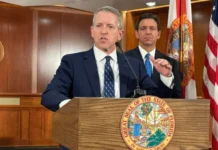 DeSantis Signals Preferred Successor in Florida Governor’s Race Former Florida House Speaker Paul Renner speaks at a podium while Gov. Ron DeSantis stands behind him during an official event in Florida.